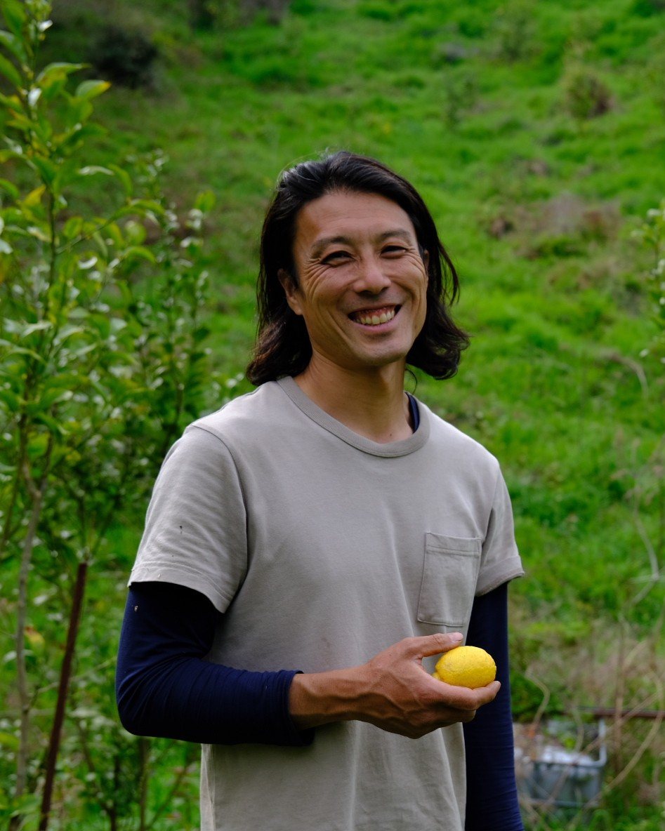 畑でレモンを手に笑う松井さん